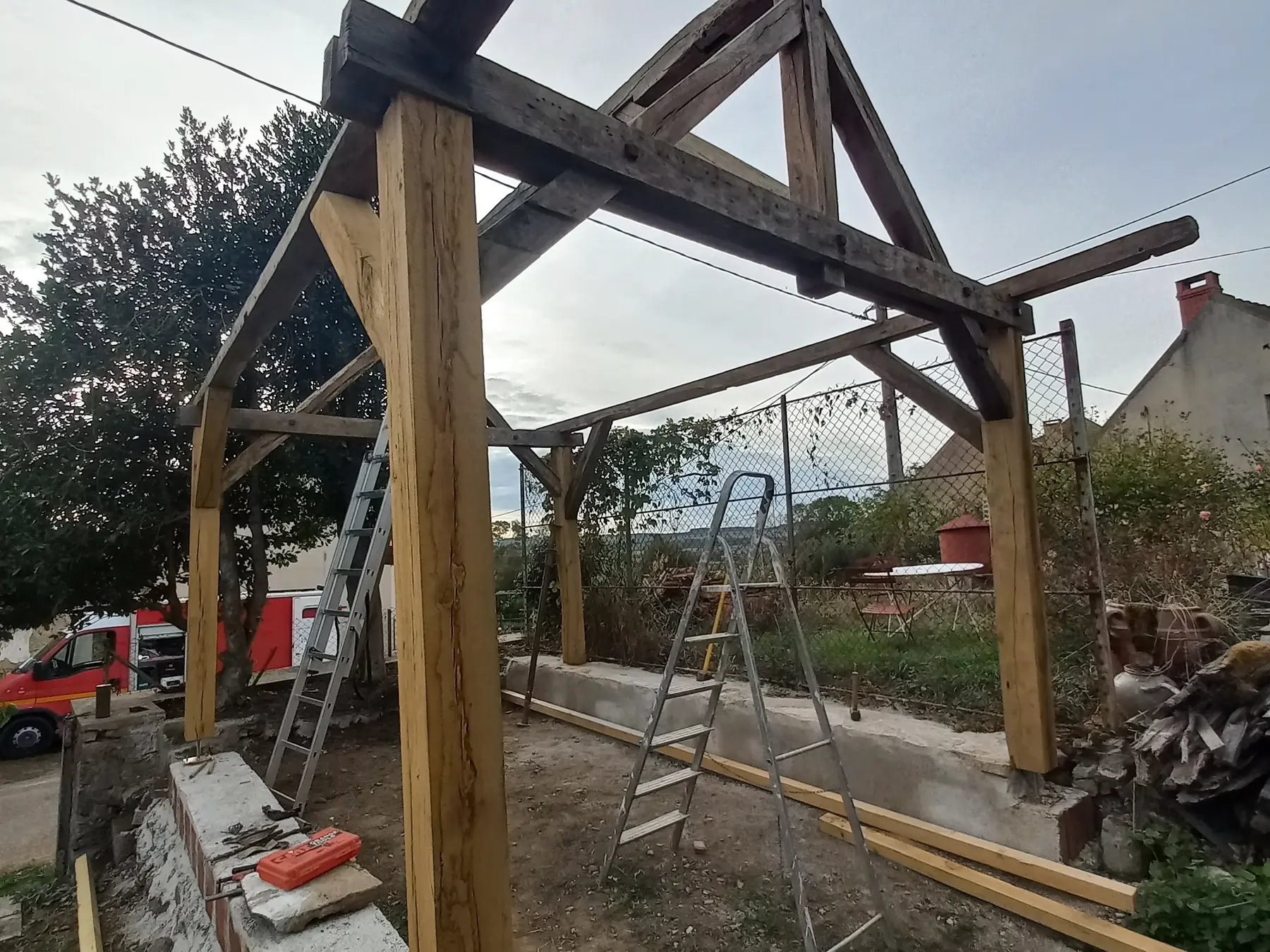 Charpente bois d’un abri permanent en cours de montage dans un jardin