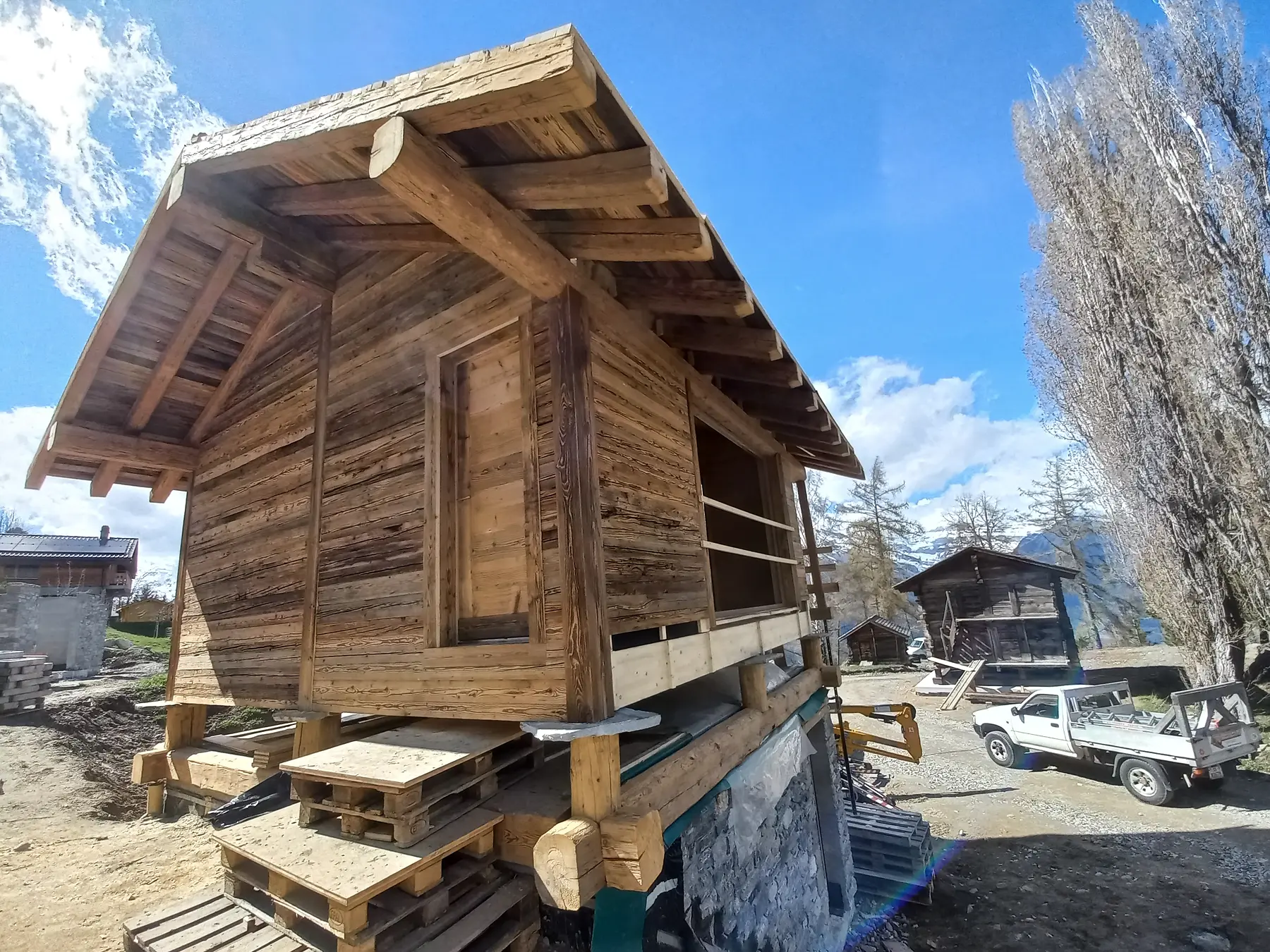 Petite cabane en bois en cours de construction dans un paysage de montagne